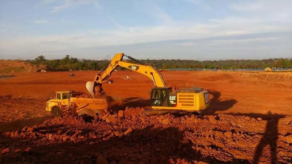 Excavator loading soil into a dump truck on a grading project
