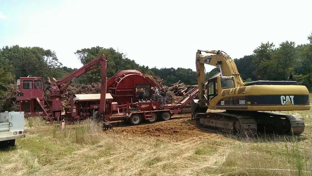 Land clearing machinery and excavator at a mulch processing site
